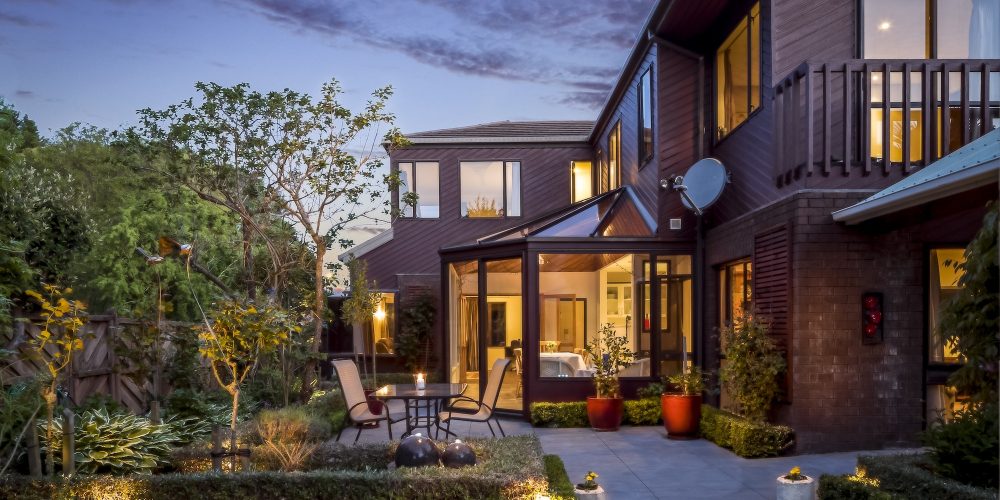 Big private house with a garden under the cloudy sky at night